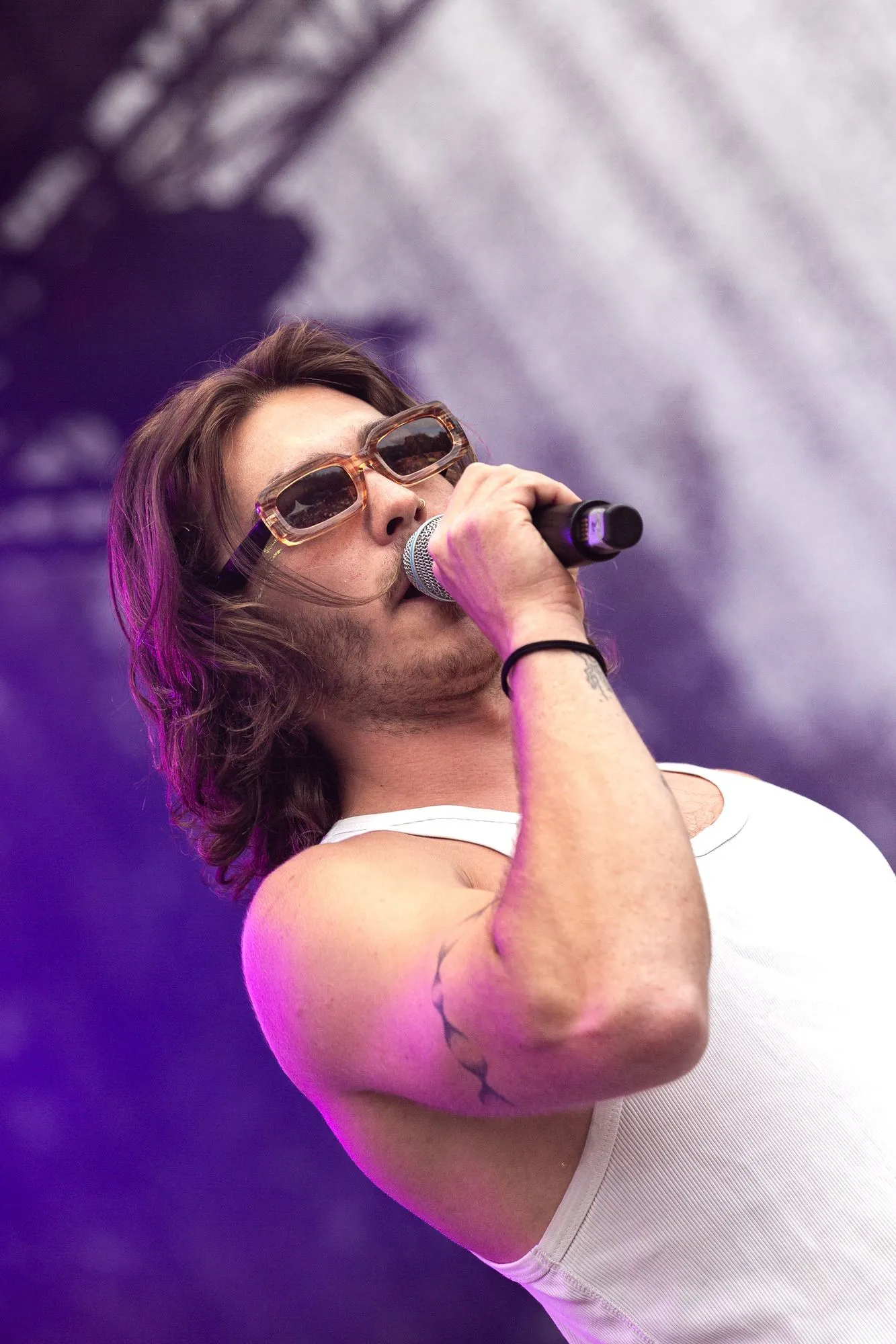 Gesang mit Sonnenbrille im weißen Tanktop, violettes Licht