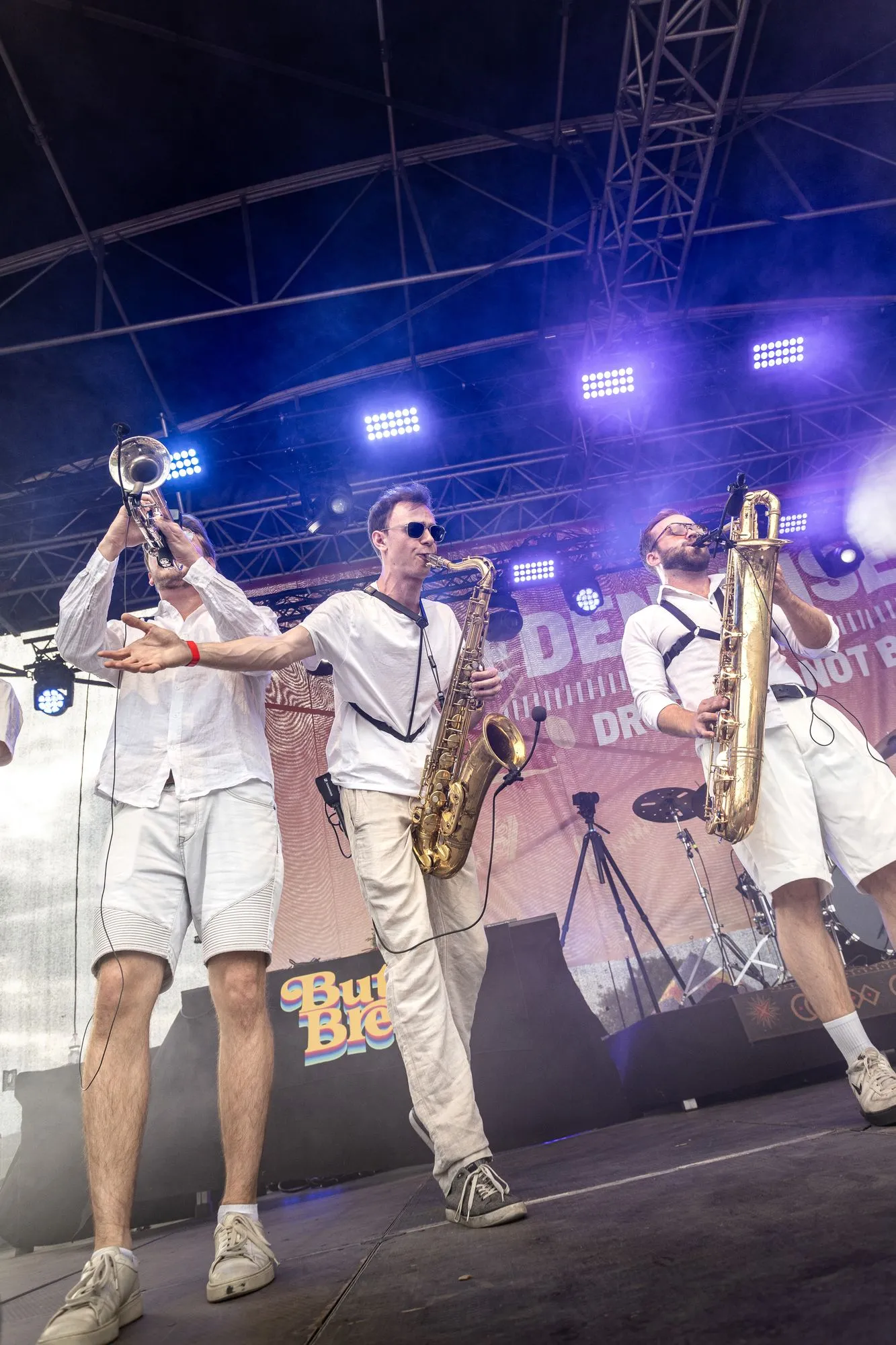 Trompete und zwei Saxofone, ganz in Weiß, springen über die Bühne