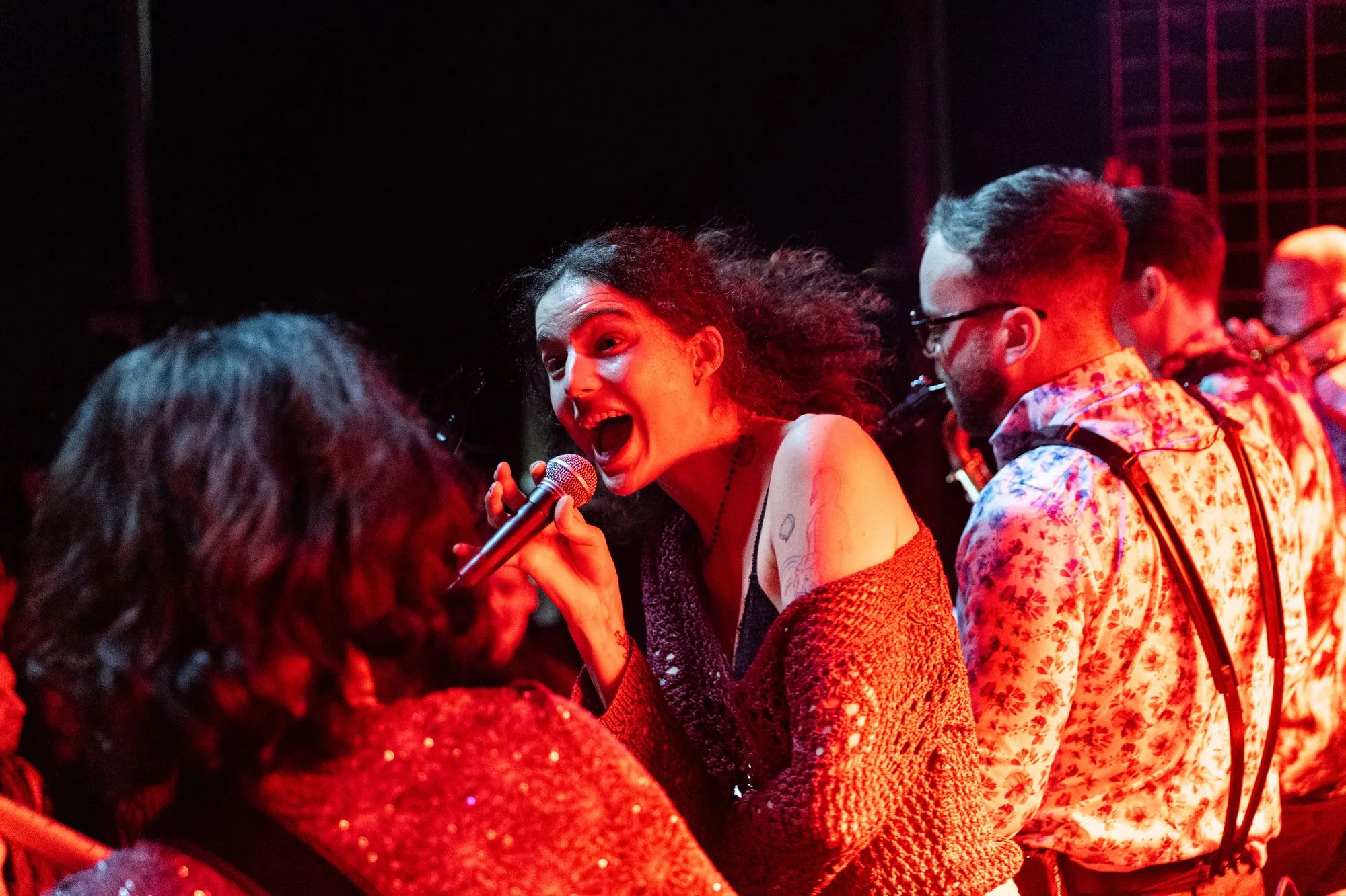 Die Sängerin singt aus voller Kehle, daneben die Bläser