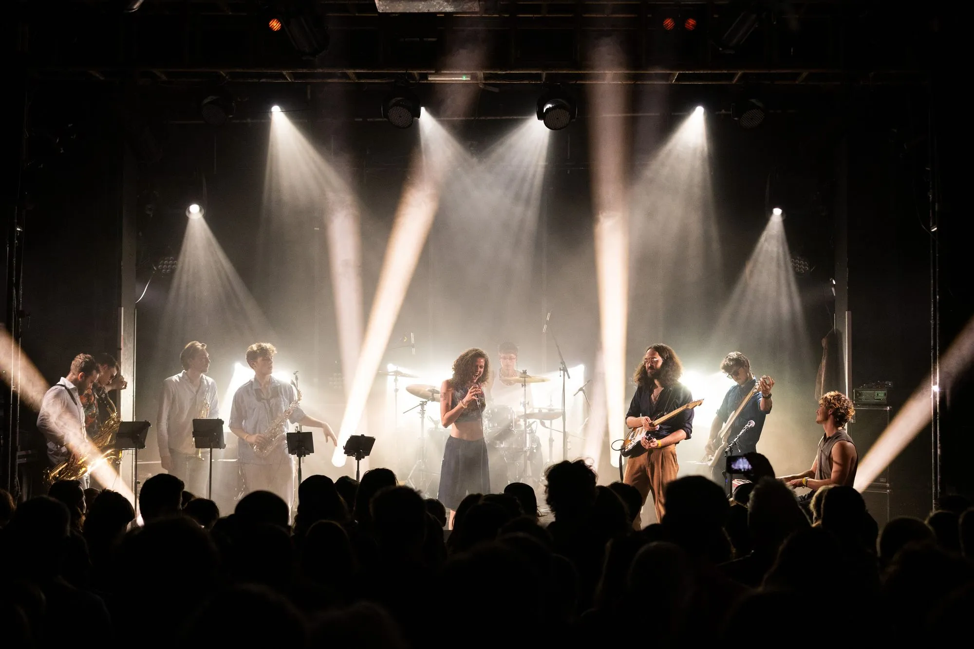 Die Band im weißen Gegenlicht, davor das Publikum