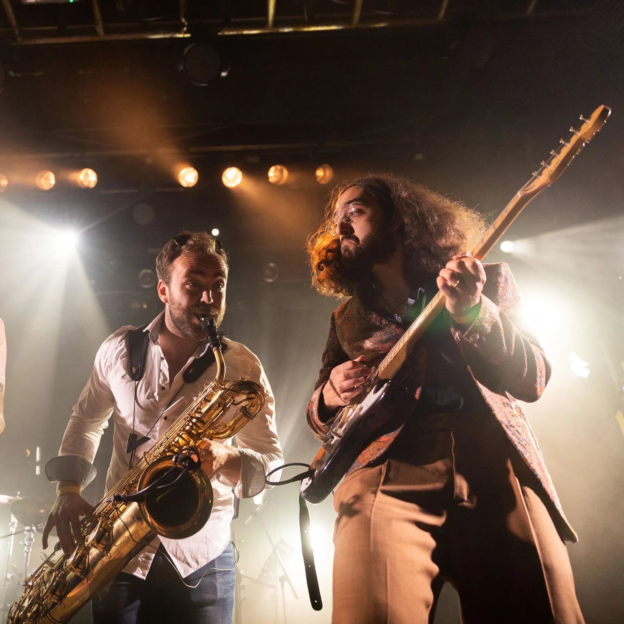 Bari sax and guitar side by side in the spotlights
