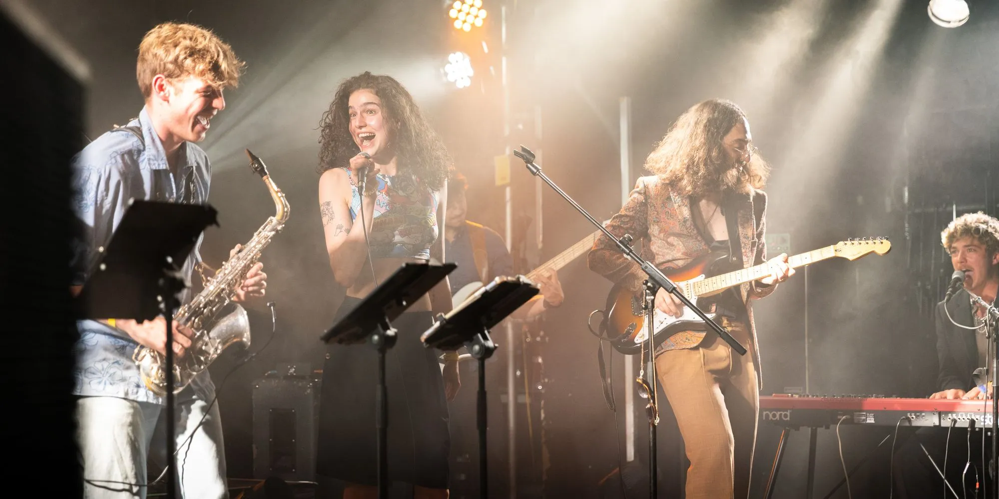 Saxofon, Gesang und Gitarre lachen im warmen Licht